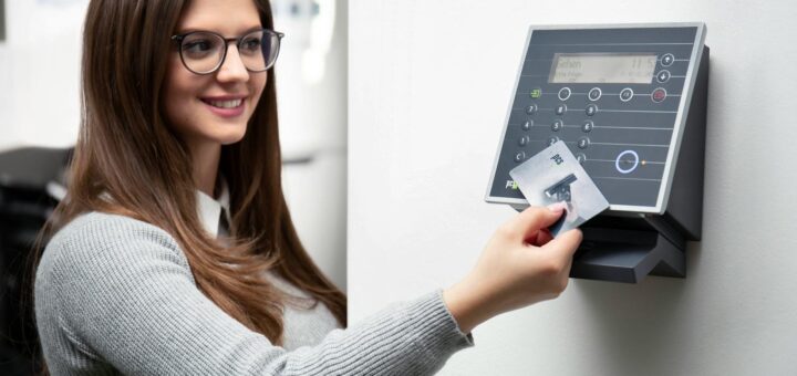 Une femme souriante utilise un lecteur de carte pour accéder en toute sécurité à son bureau.