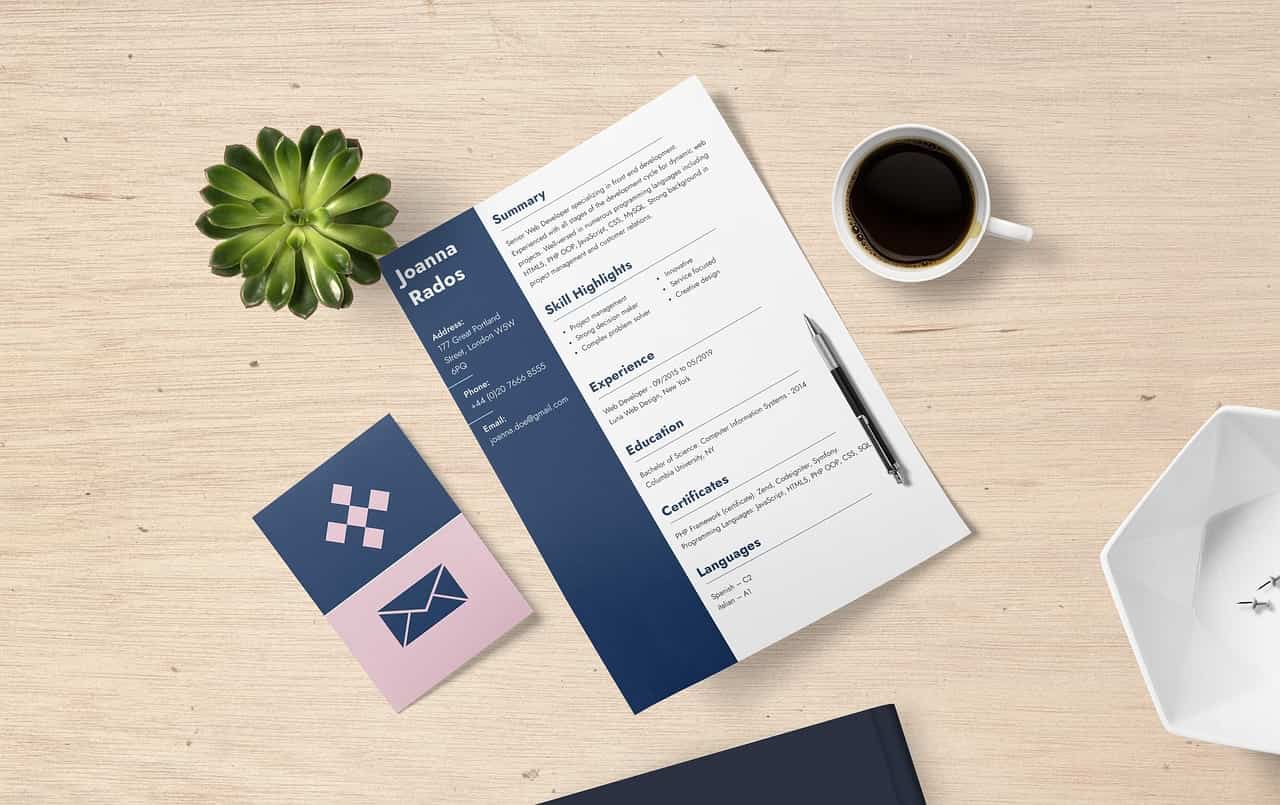 Un CV professionnel de Joanna Rados, posé sur une table en bois avec une plante succulente et une tasse de café à côté.
