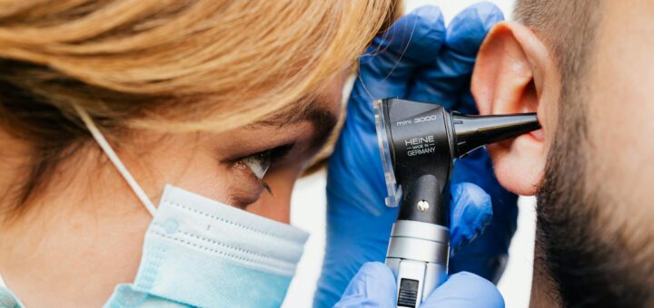 Gros plan d'un médecin effectuant un examen de l'oreille avec un otoscope.